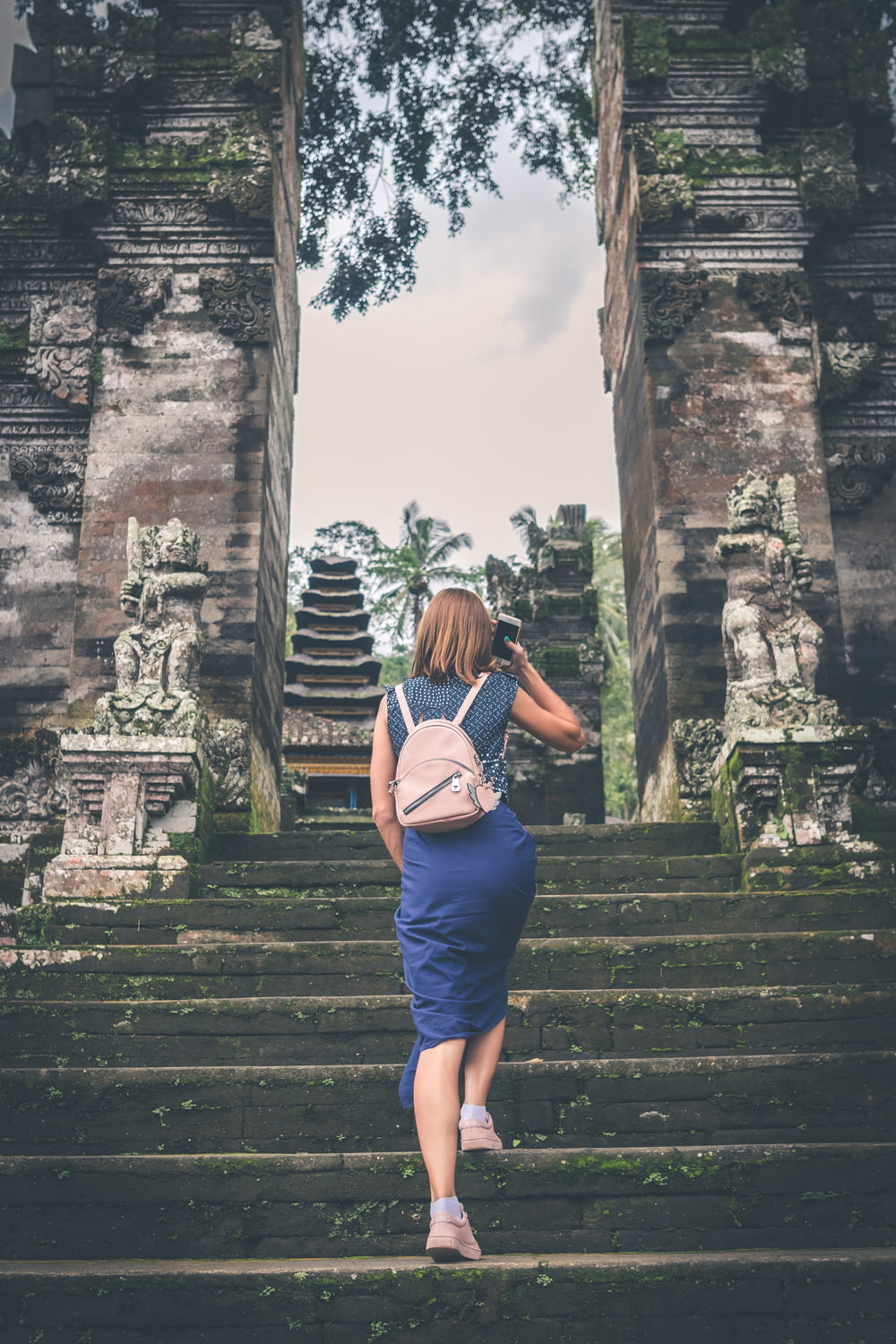 shallow focus photography of woman in blue dress walking towards temple