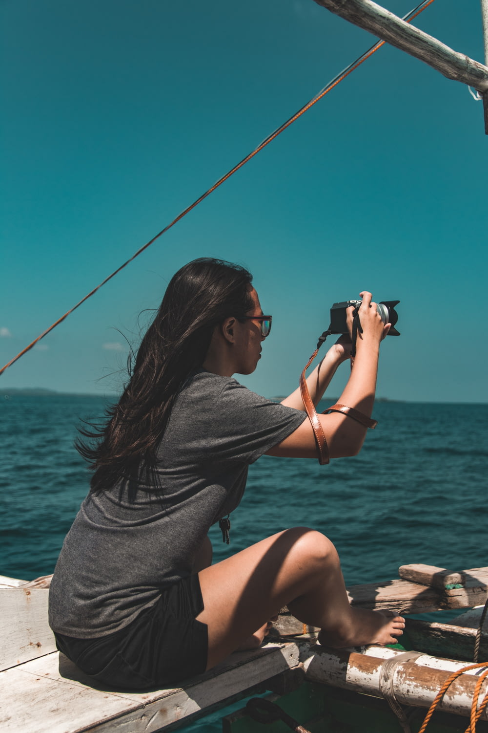 mujer sentada al lado del barco mientras sostiene la cámara DSLR