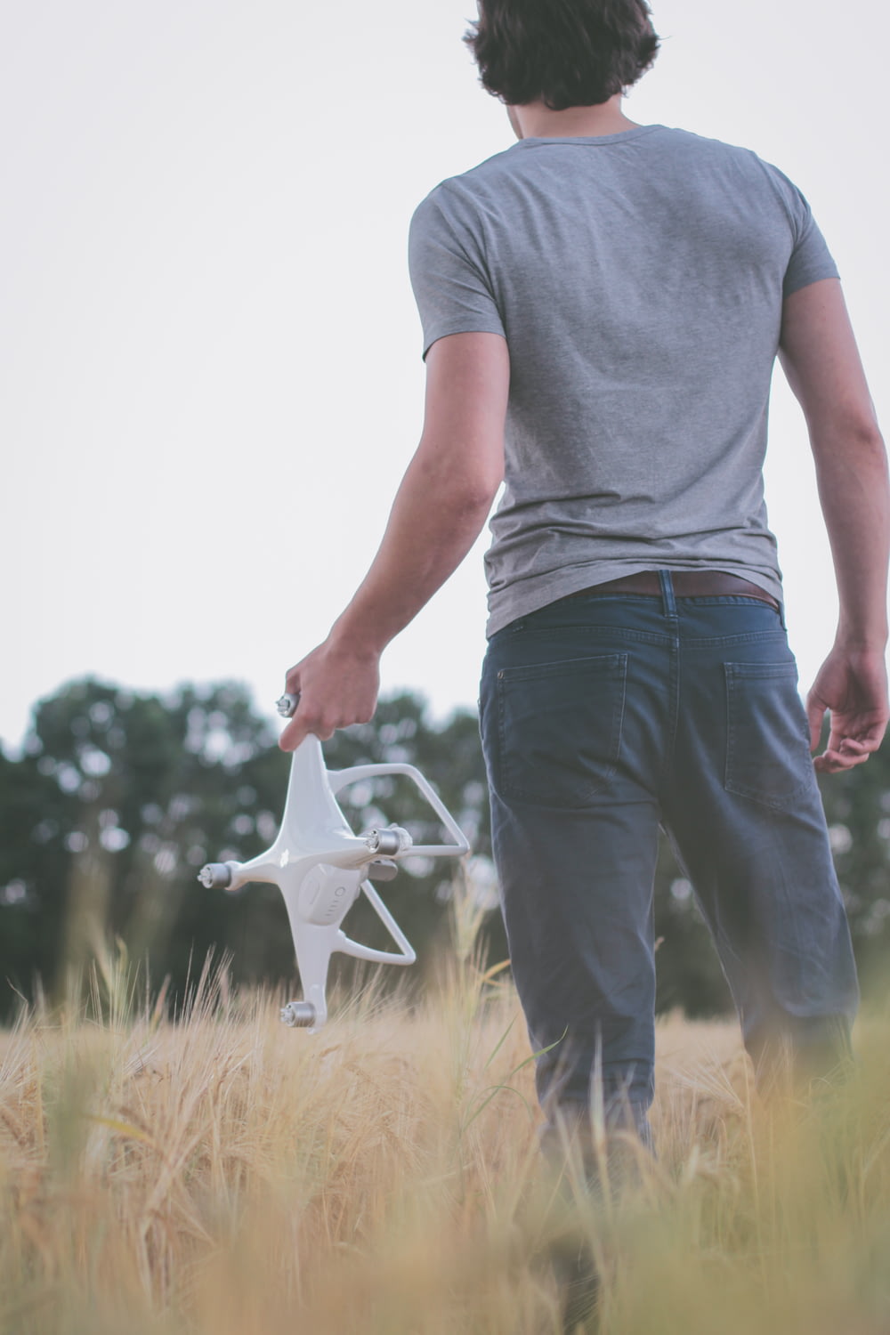 man standing on field holding white quadcopter
