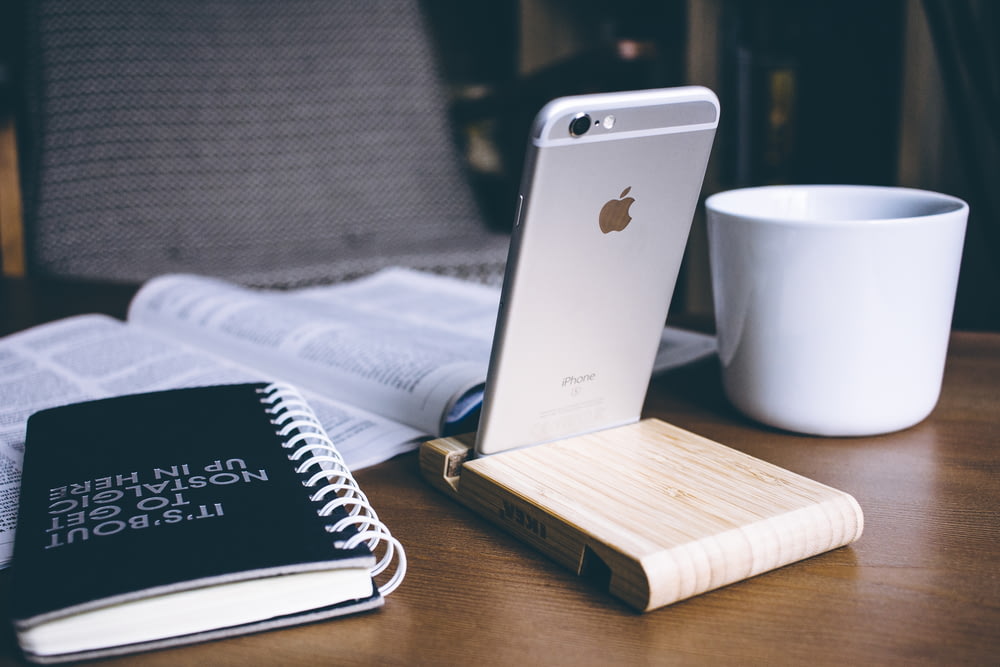 silbernes iPhone 6 neben weißem Keramikbecher