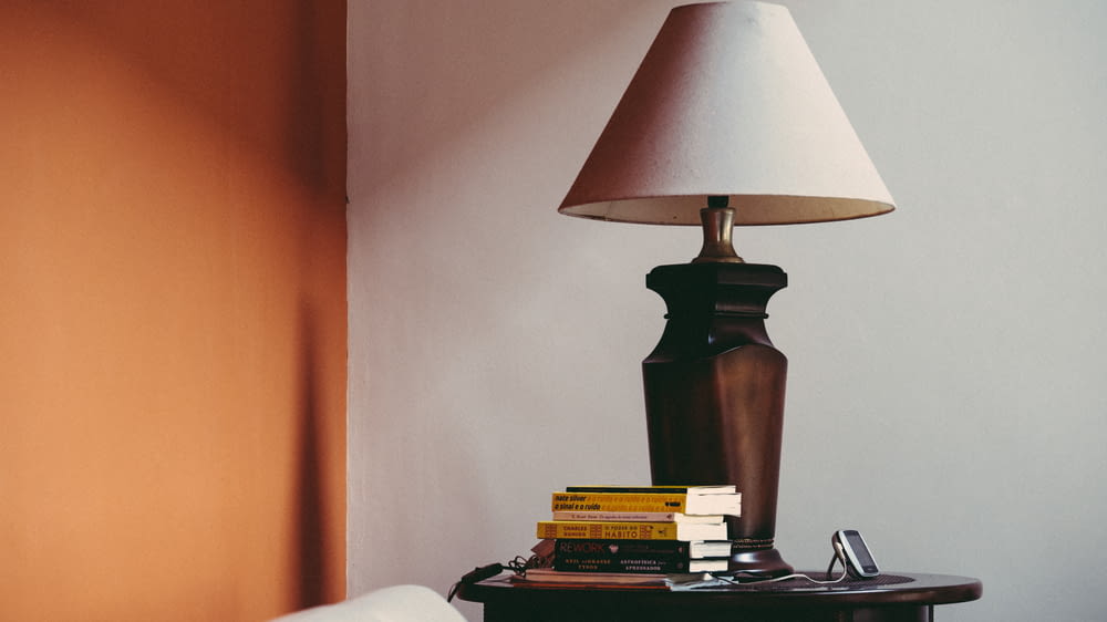 pile of books beside brown table lamp