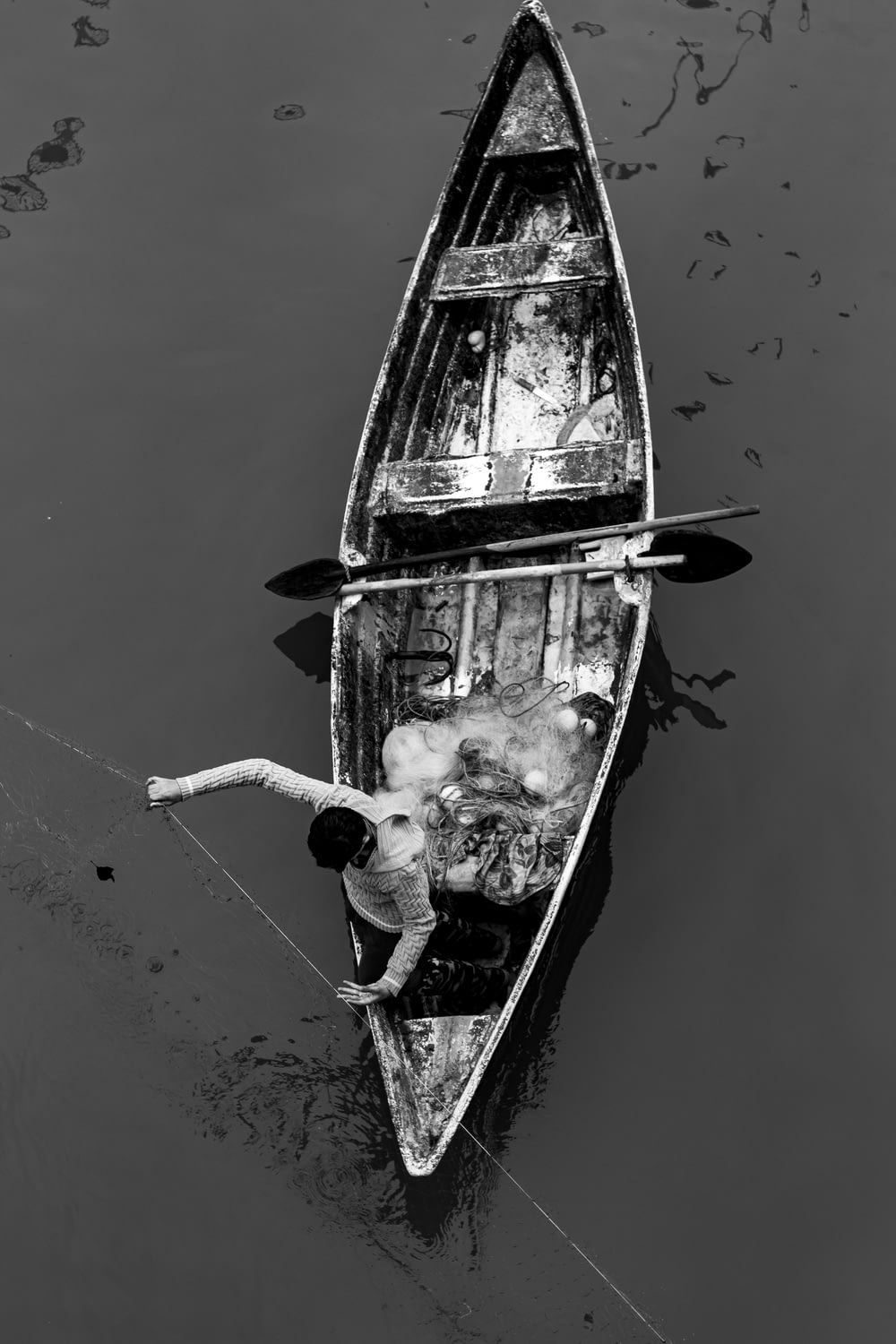 grayscale photo of person fishing on white boat