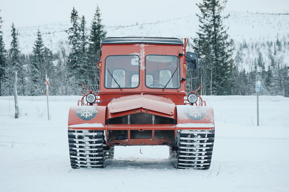 red vehicle passes on road coated snow