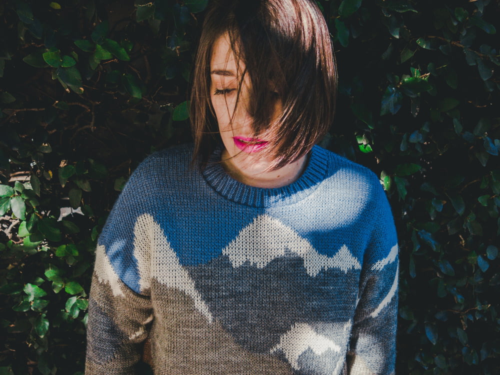 woman wearing sweater near green grass wall