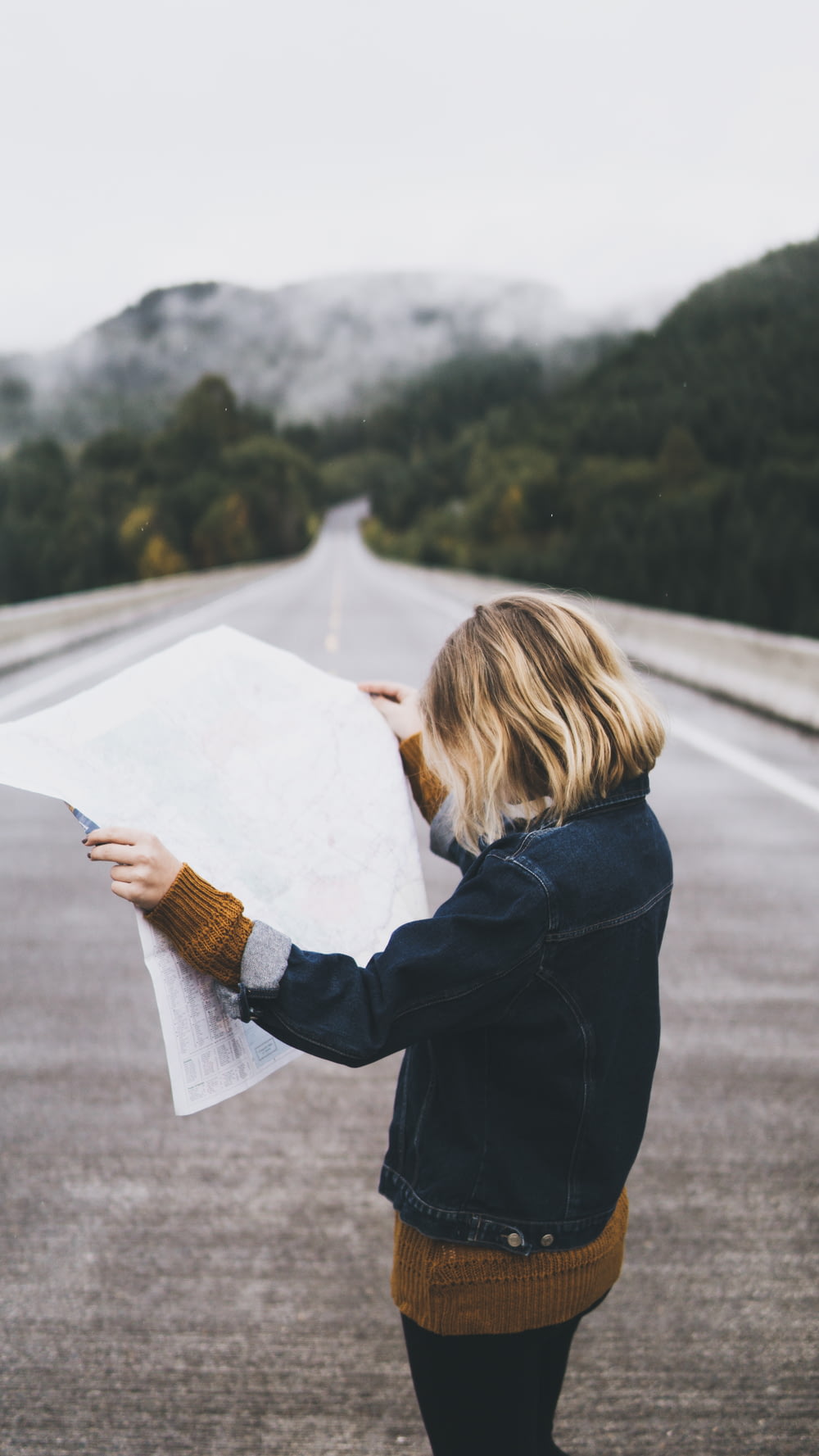 Mujer mirando el mapa mientras está parada en la carretera