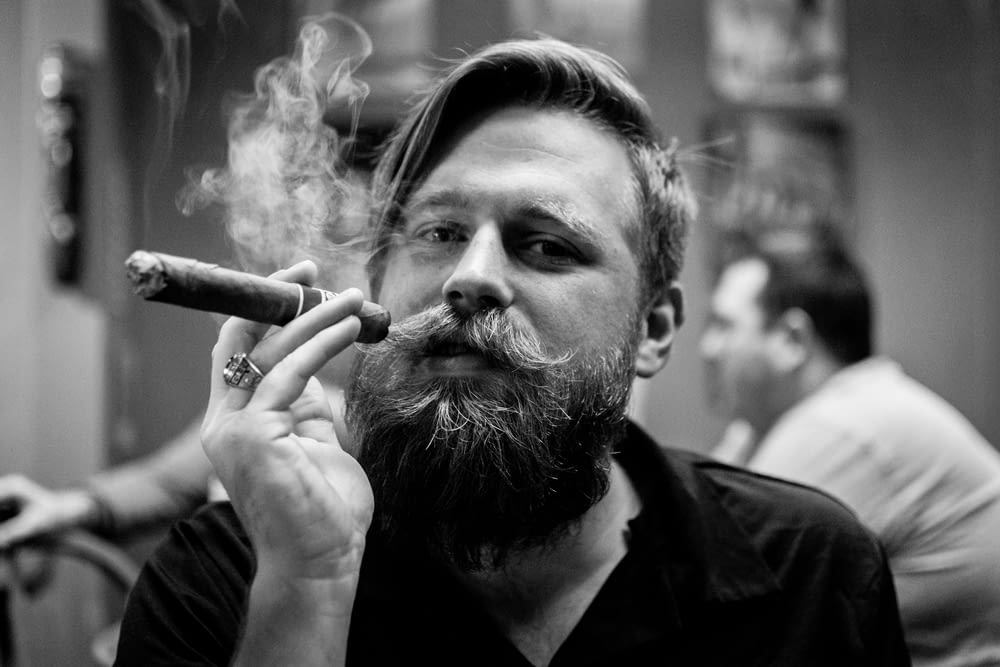 fotografia di ritratto in scala di grigi di persona che fuma sigaro