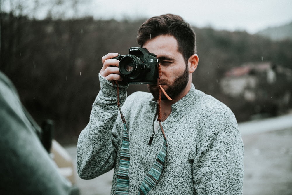 selective focus photography of man holding DSLR camera