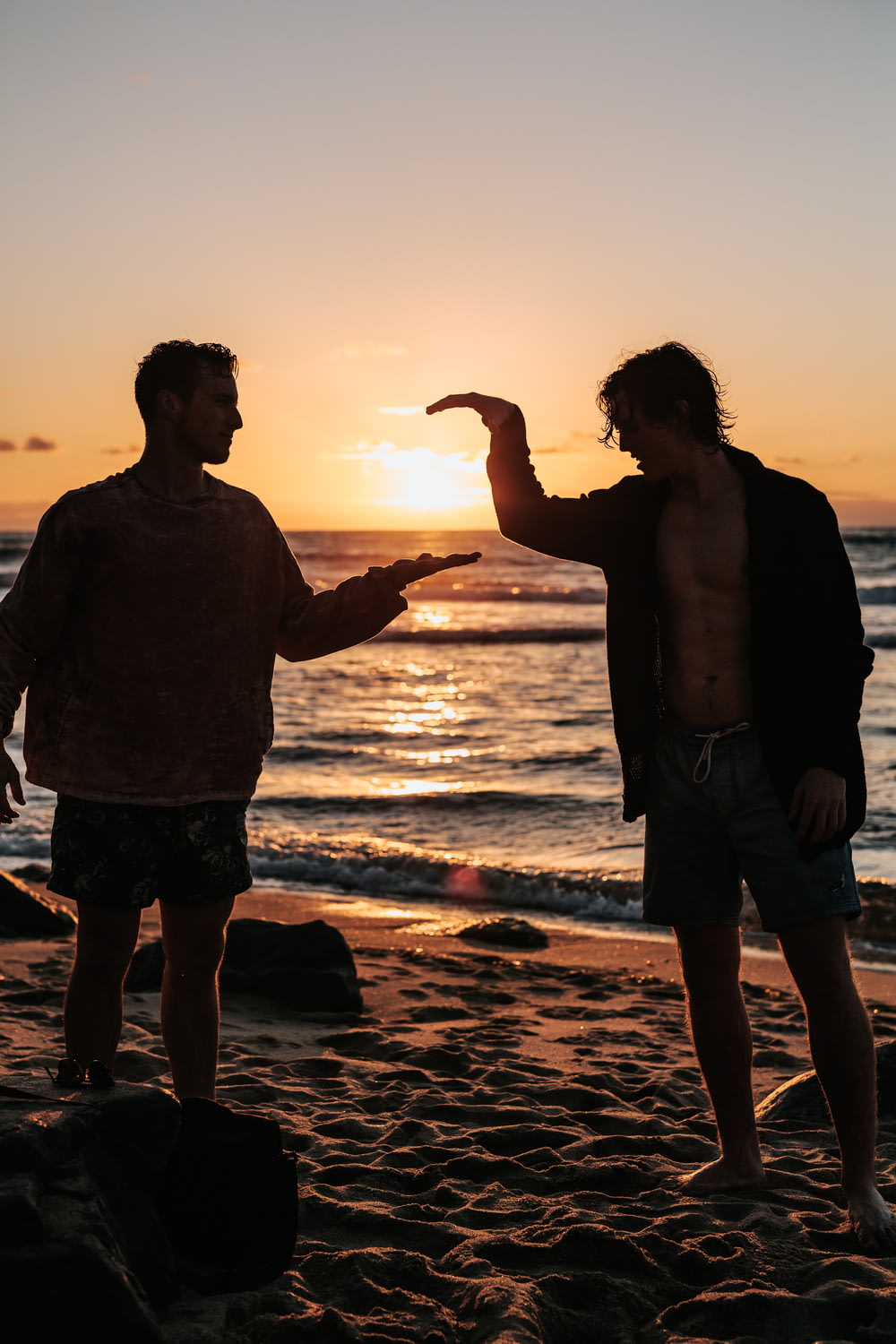 夕暮れ時にビーチの近くで握手を交わす2人の男性のクローズアップ写真