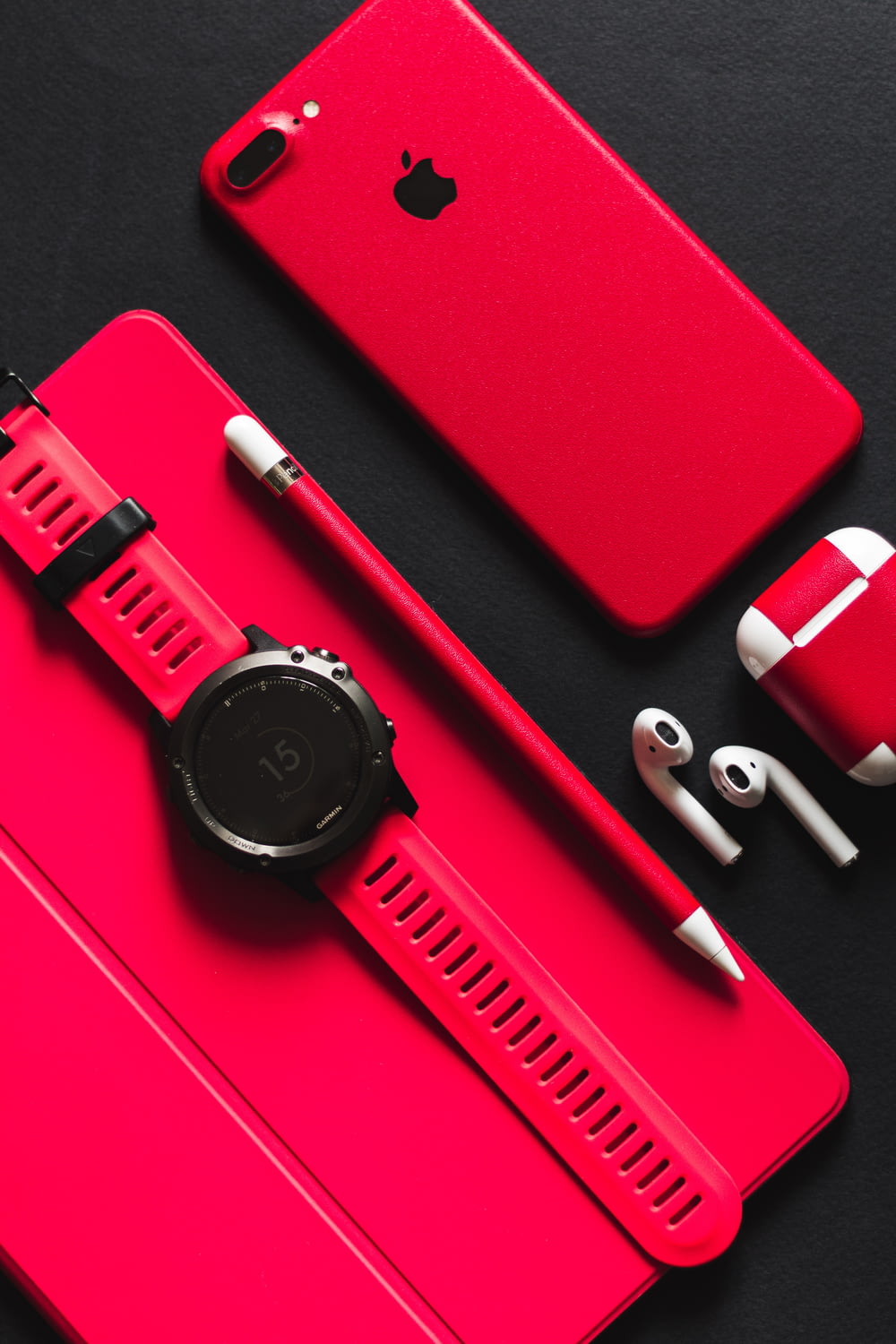 smartwatch, stylus, AirPods, and product red iPhone 7 on black surface