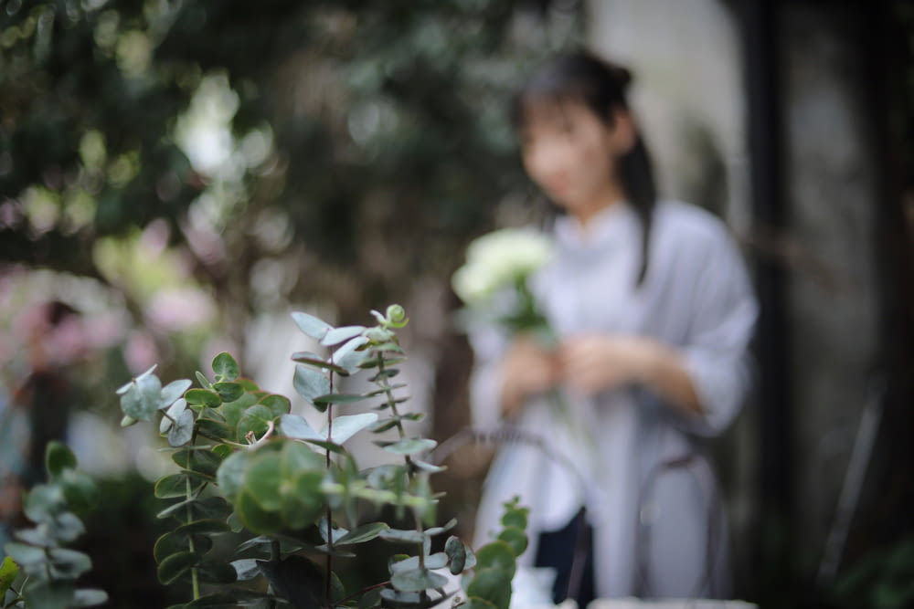 selective focus photography of plant near standing woman