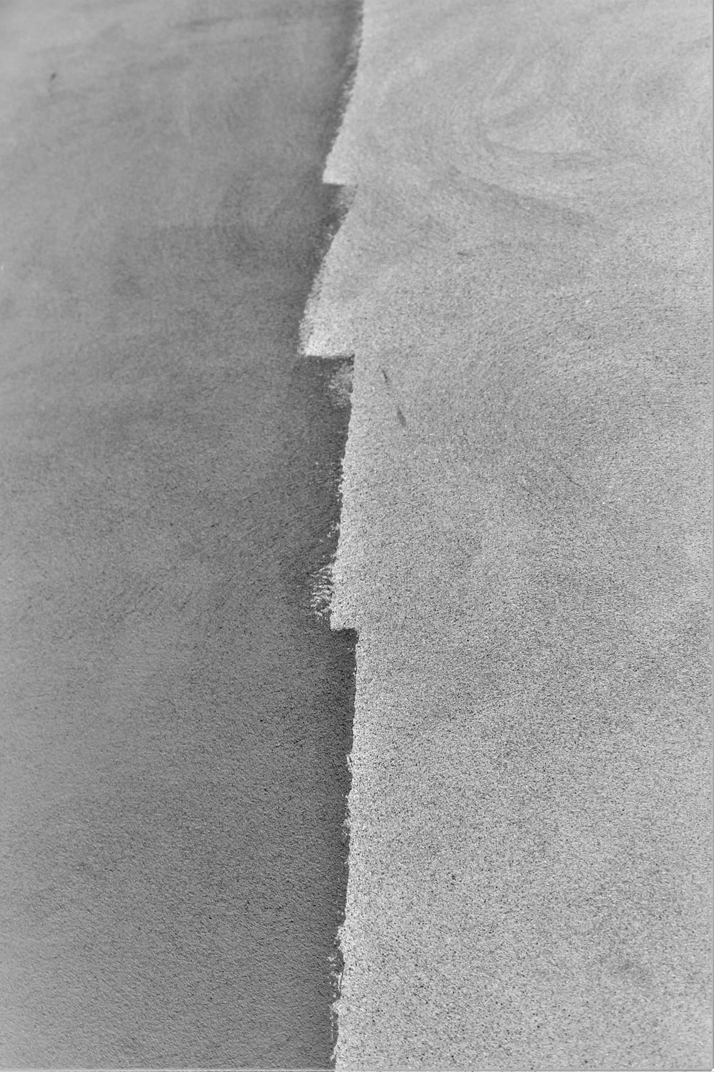 a black and white photo of a wave in the sand