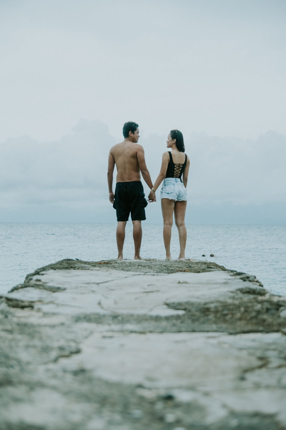 man and woman holding hands standing on edge of cliff