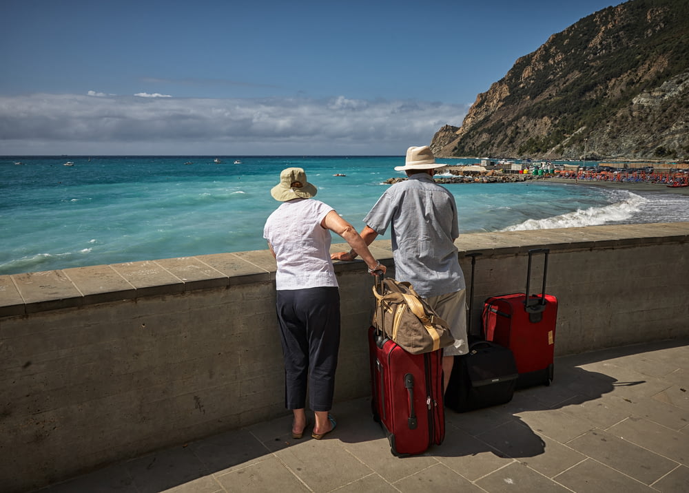 hombre y mujer de pie junto al malecón de hormigón mirando a la playa