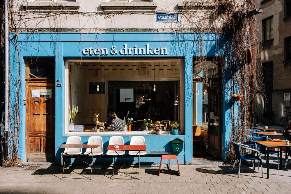 Fachada azul y blanca de la tienda Eten & Drinken durante el día