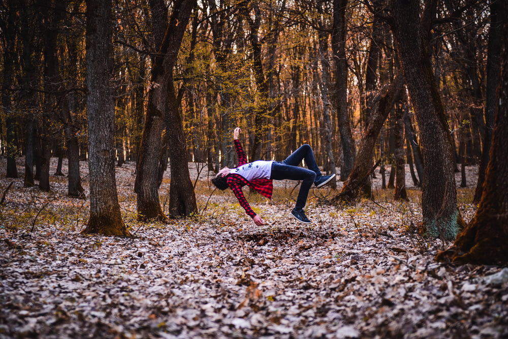 a woman is doing a handstand in the woods