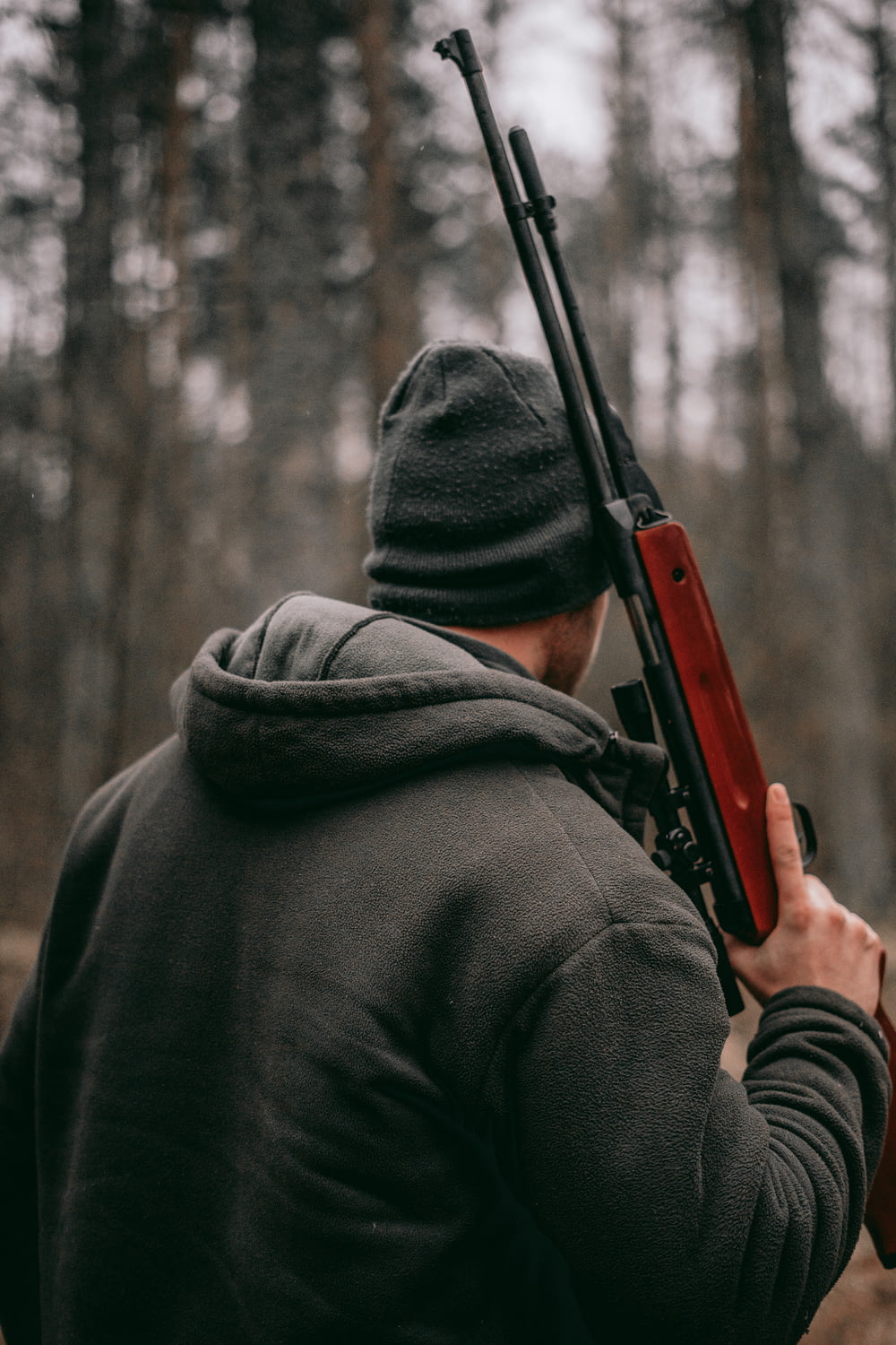 homme tenant un fusil de sniper brun et noir dans une photographie à mise au point peu profonde