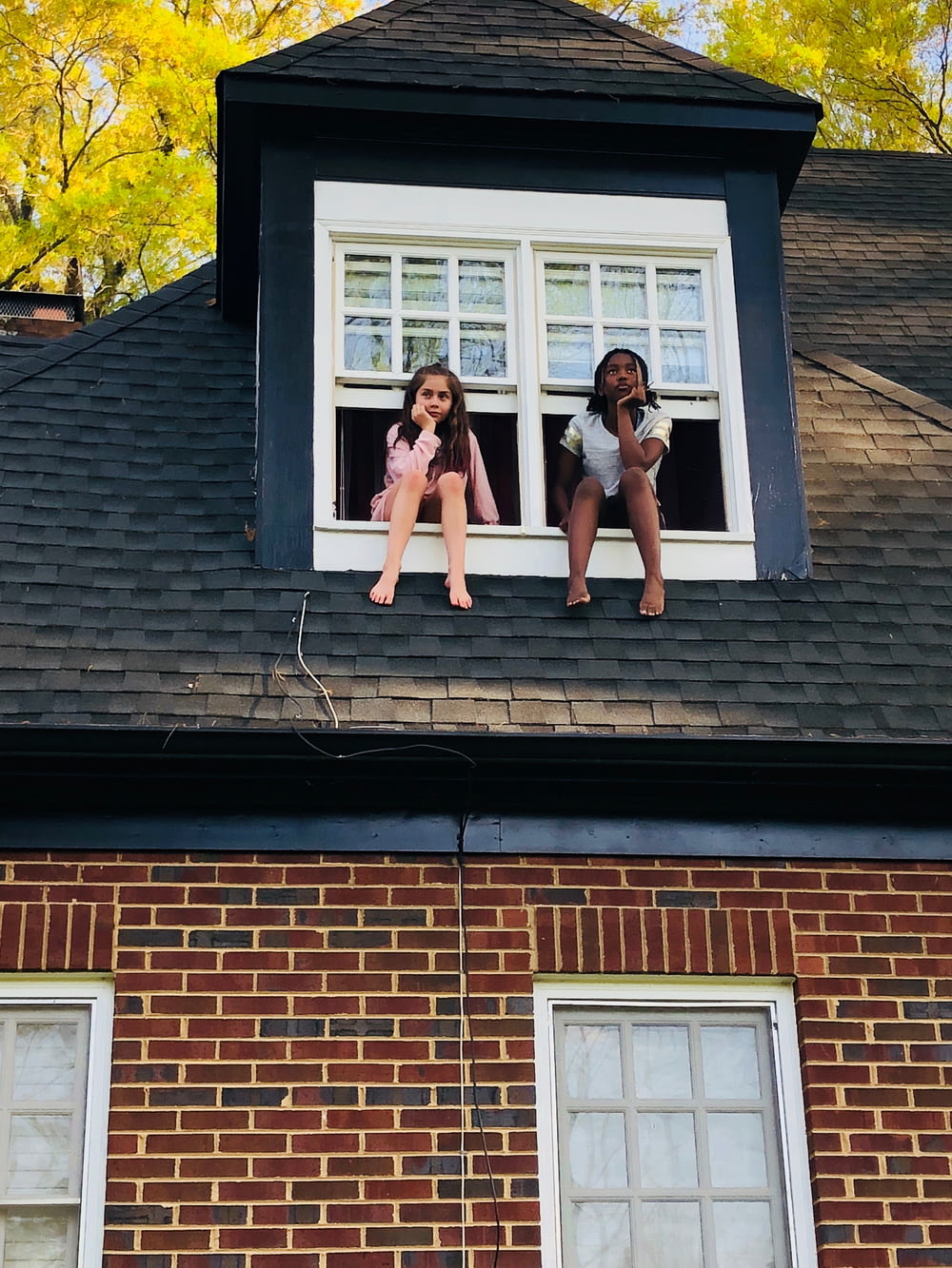 昼間、白い2枚窓に座る2人の少女
