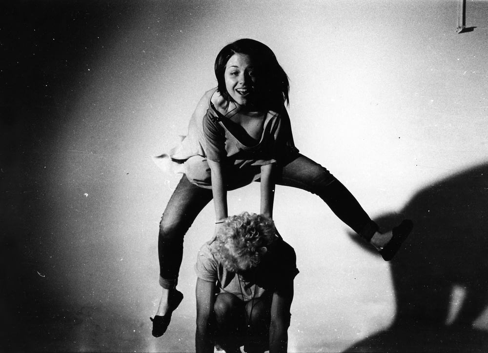 mulher pulando nas costas de outra pessoa em fotografia em tons de cinza