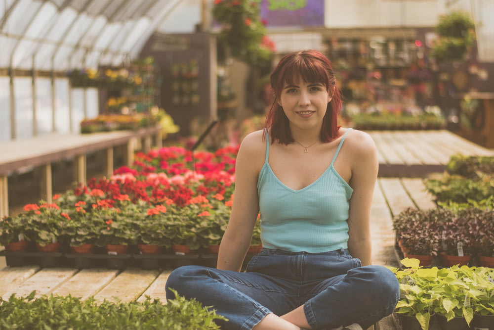 woman sitting inside green house beside plants