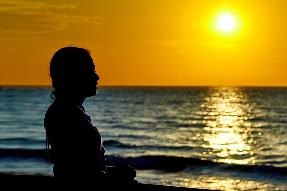 woman standing infront of beach during sunset