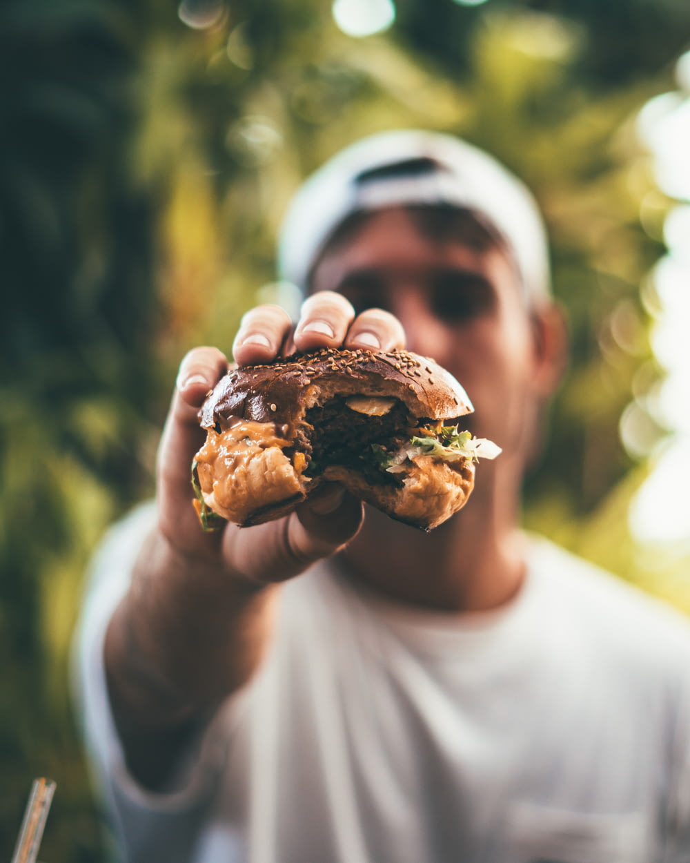 photographie sélective de mise au point de l’homme tenant un hamburger mangé
