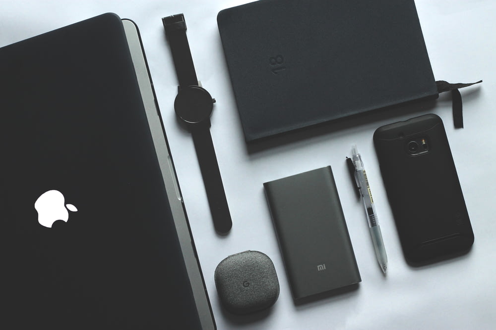 schwarzes MacBook, Uhr, Smartphone und Notebook