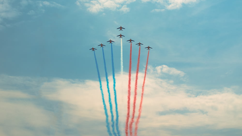 Aviones azules, rojos y blancos en vuelo creando estelas de condensación
