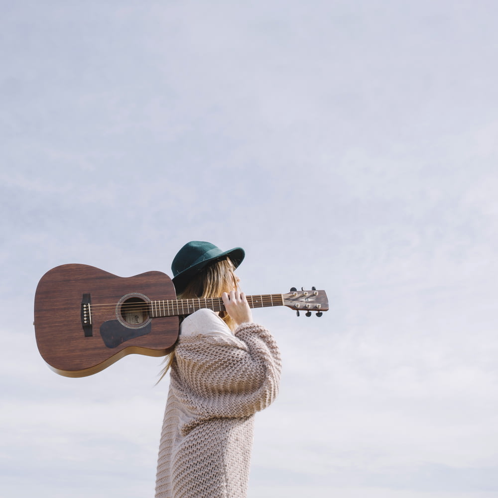 femme portant une guitare acoustique brune