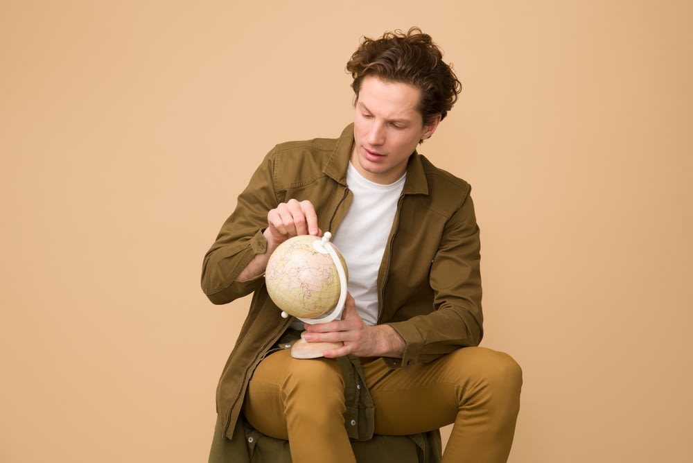 man holding globe while on sit