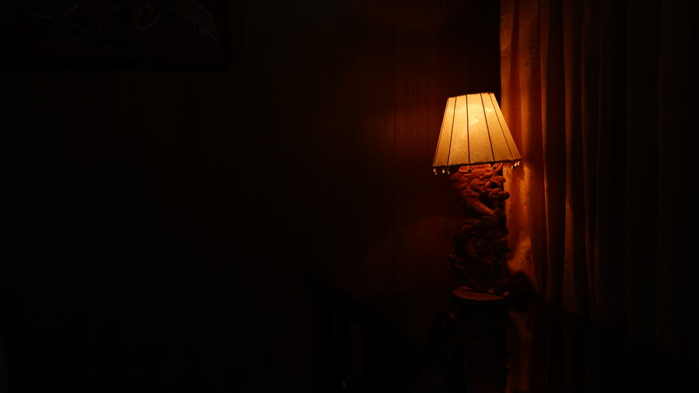 薄暗い部屋の近くでの照明付きテーブルランプの写真撮影
