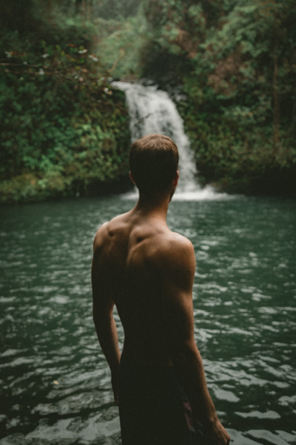 man facing waterfalls at daytime