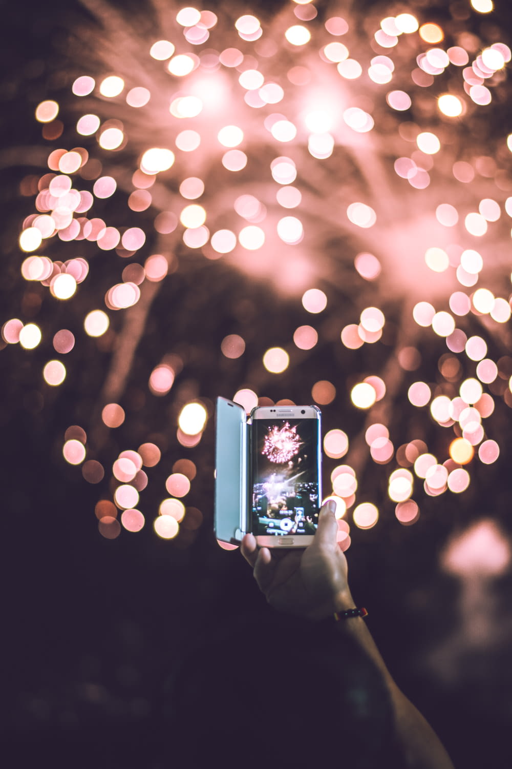 person taking video of pink firework display