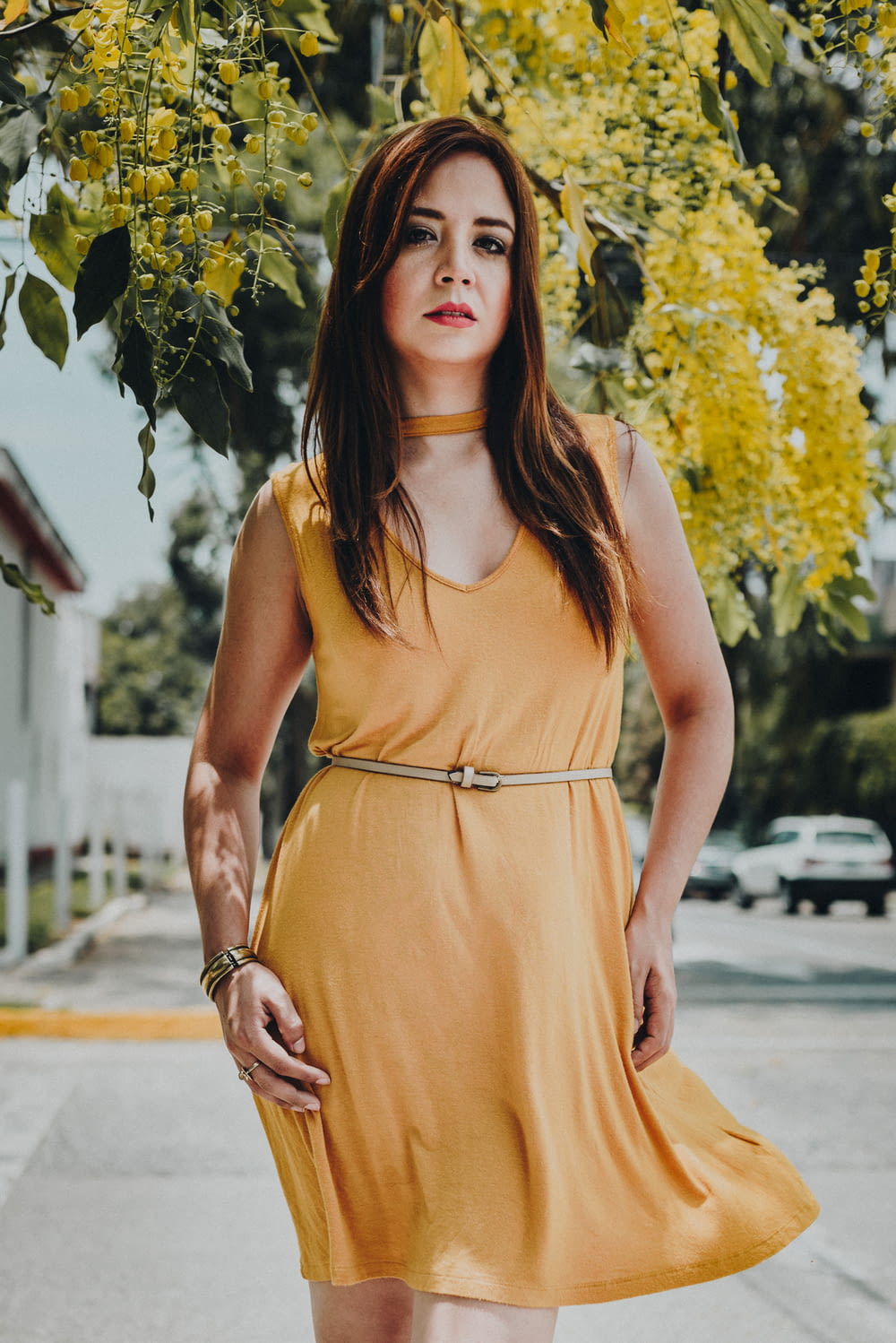 woman wearing orange sleeveless dress standing near yellow flower tree