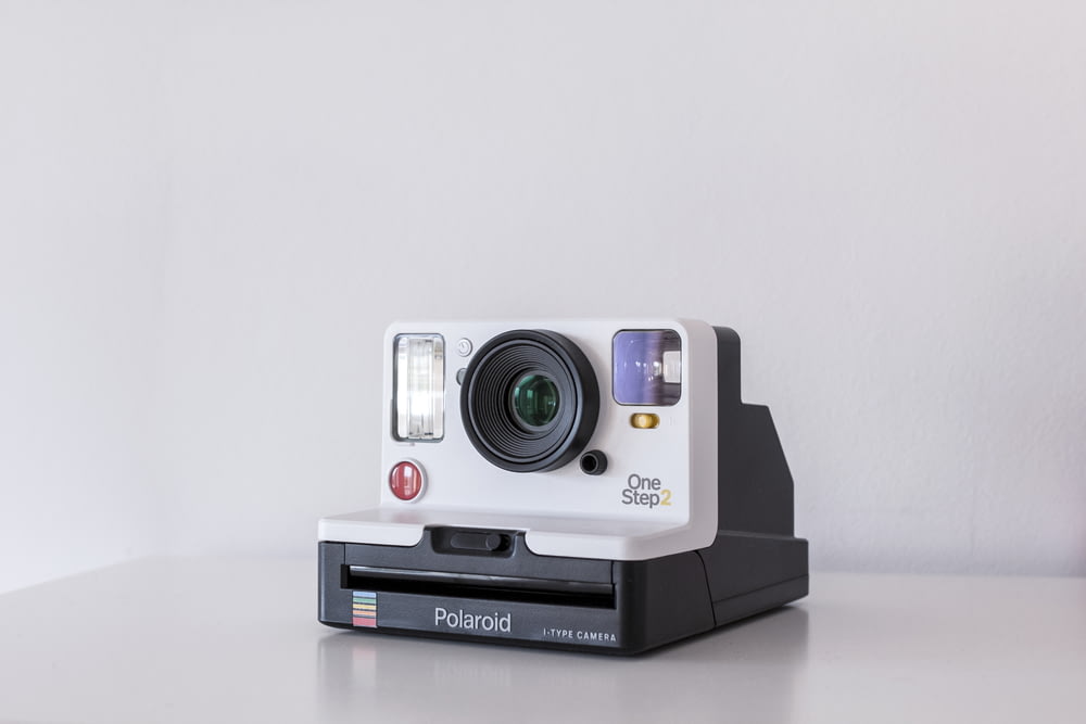câmera instantânea Polaroid One Step 2 branca e preta no quadro branco