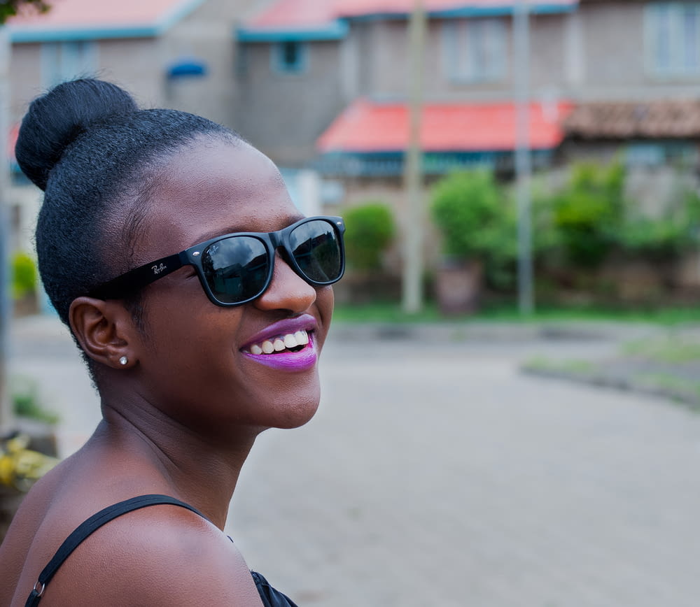 woman wearing black Ray-Ban Wayfarer-style sunglasses smiling