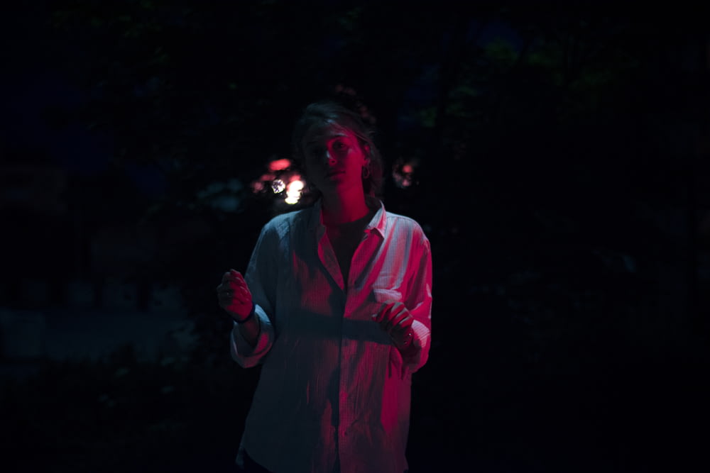 a woman standing in the dark holding a lit object