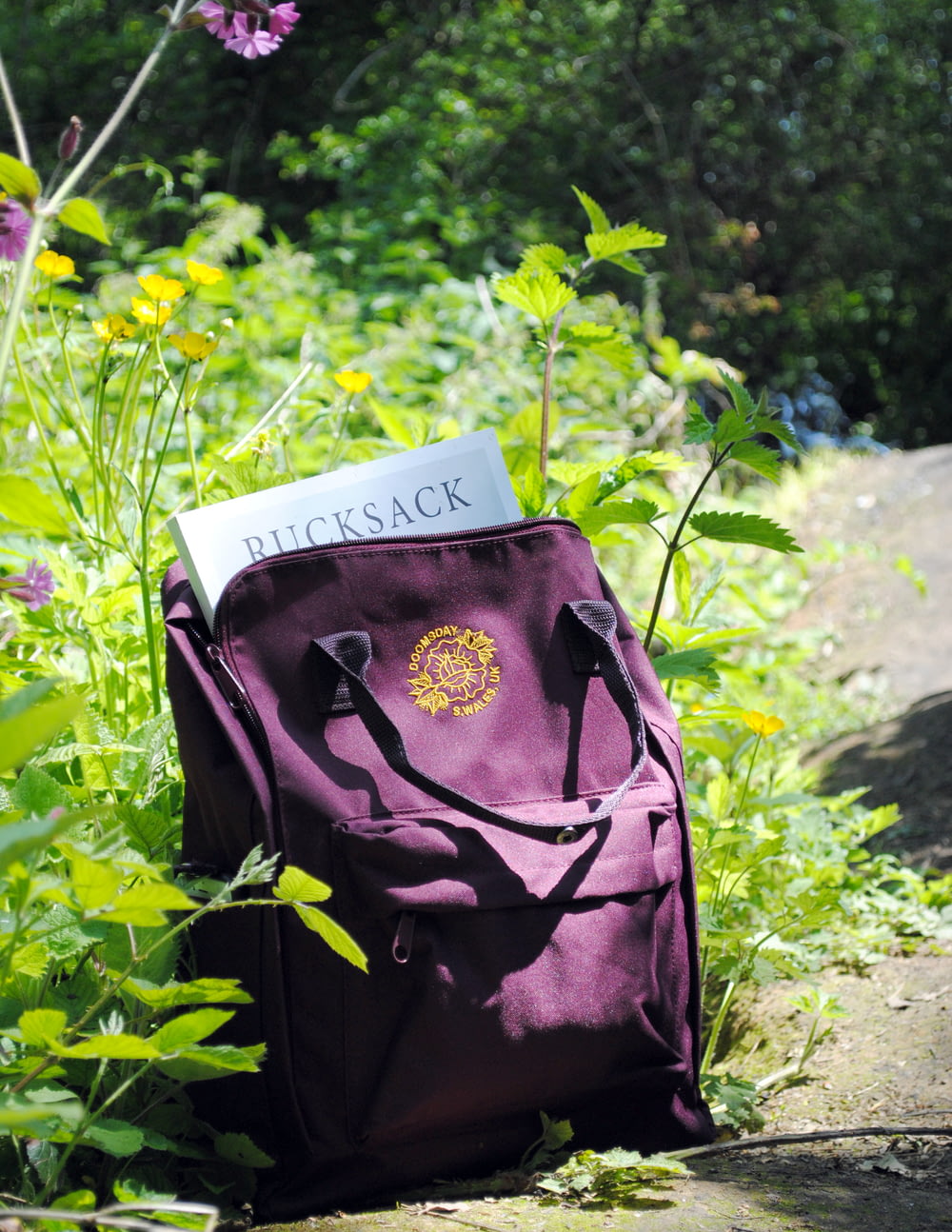花びらの花の横の紫色の革のバックパック