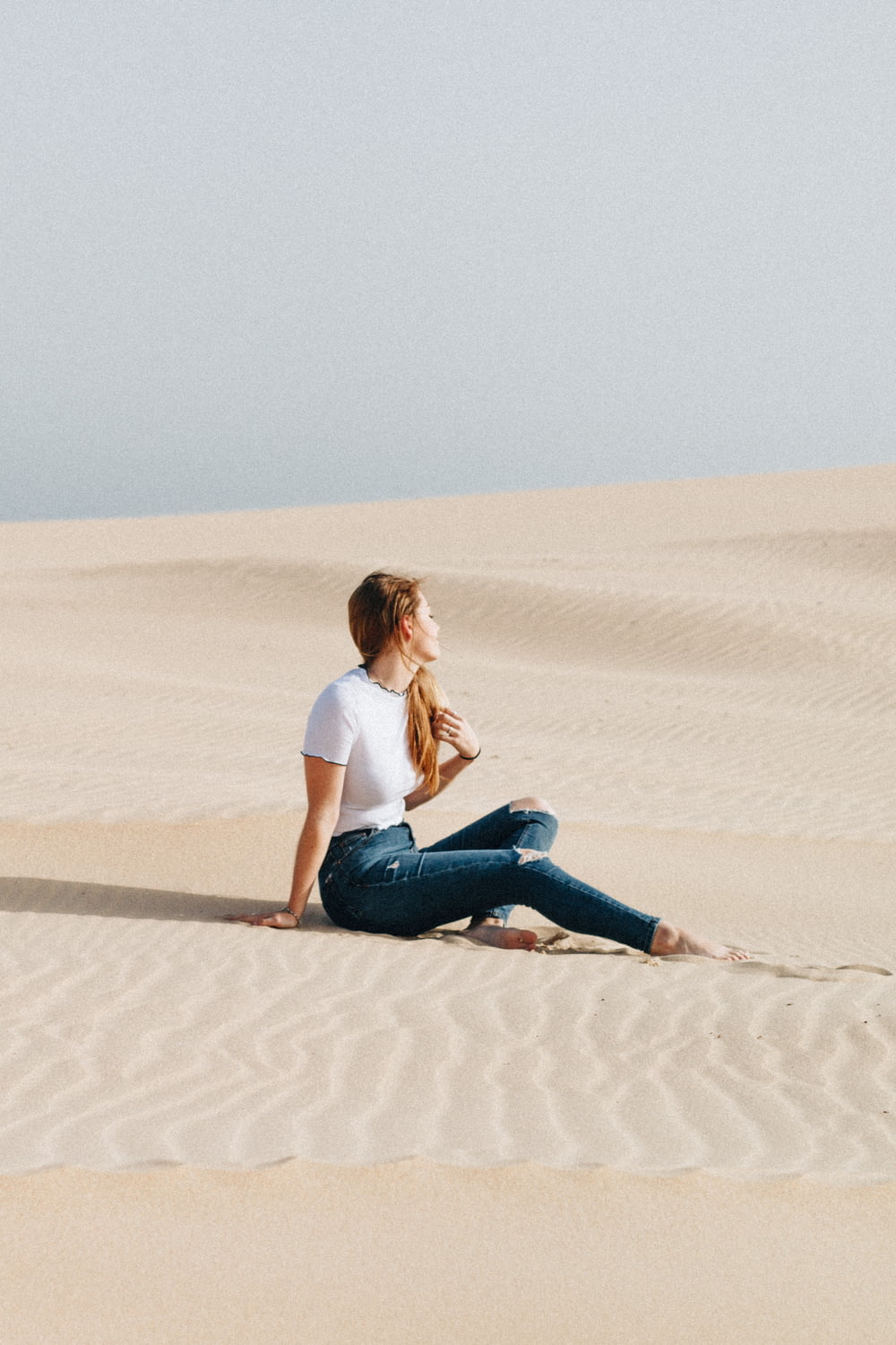 woman sitting on desert at daytime