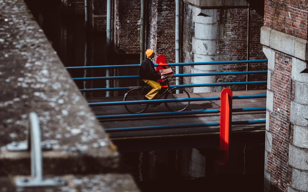 낮에 회색 콘크리트 다리에서 자전거를 타는 남자
