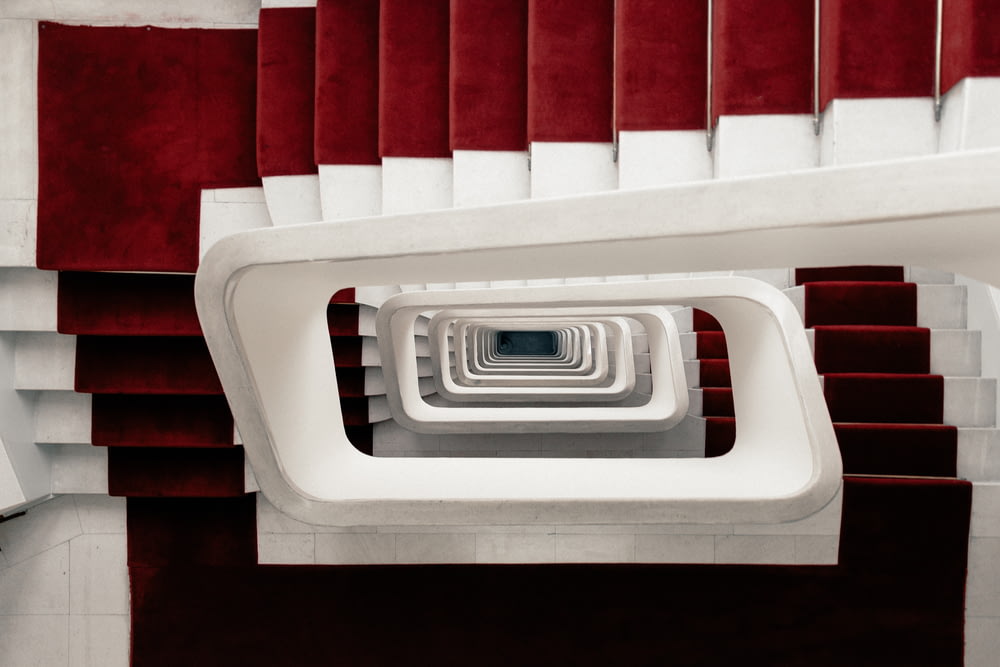 Photo en plongée d’escaliers en colimaçon avec tapis rouge