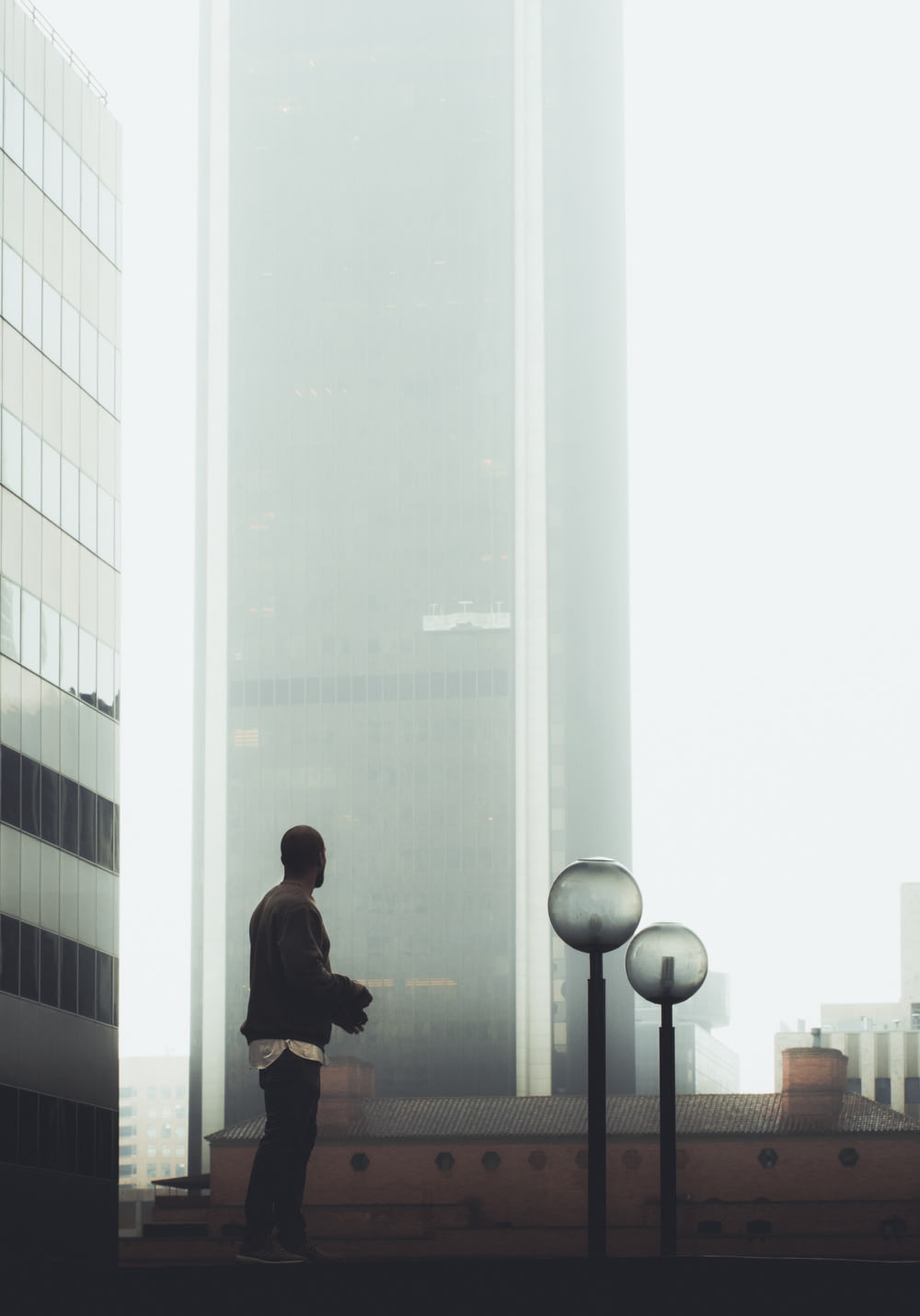 homem em pé perto do edifício de vidro durante o dia