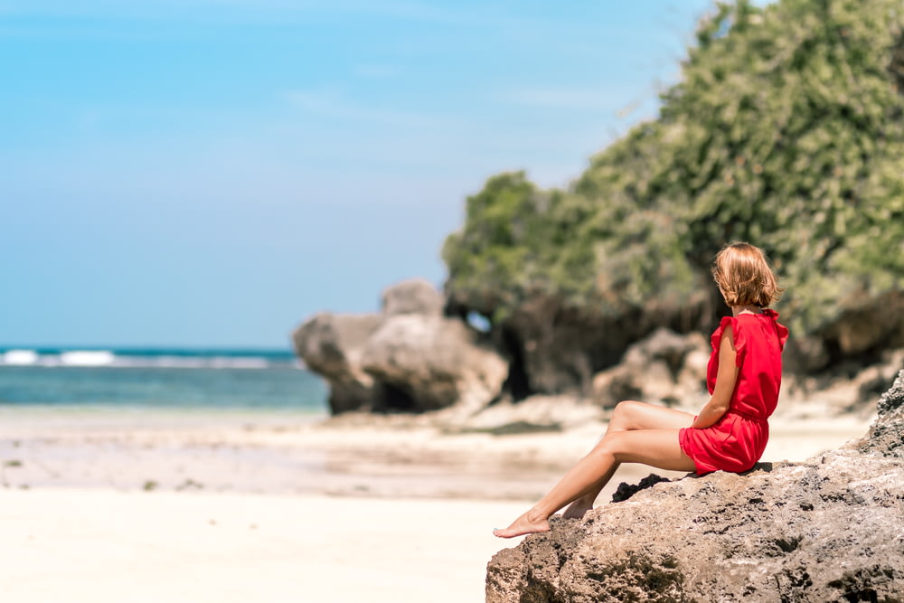 photo de mise au point sélective d’une femme assise sur le rivage de la formation rocheuse