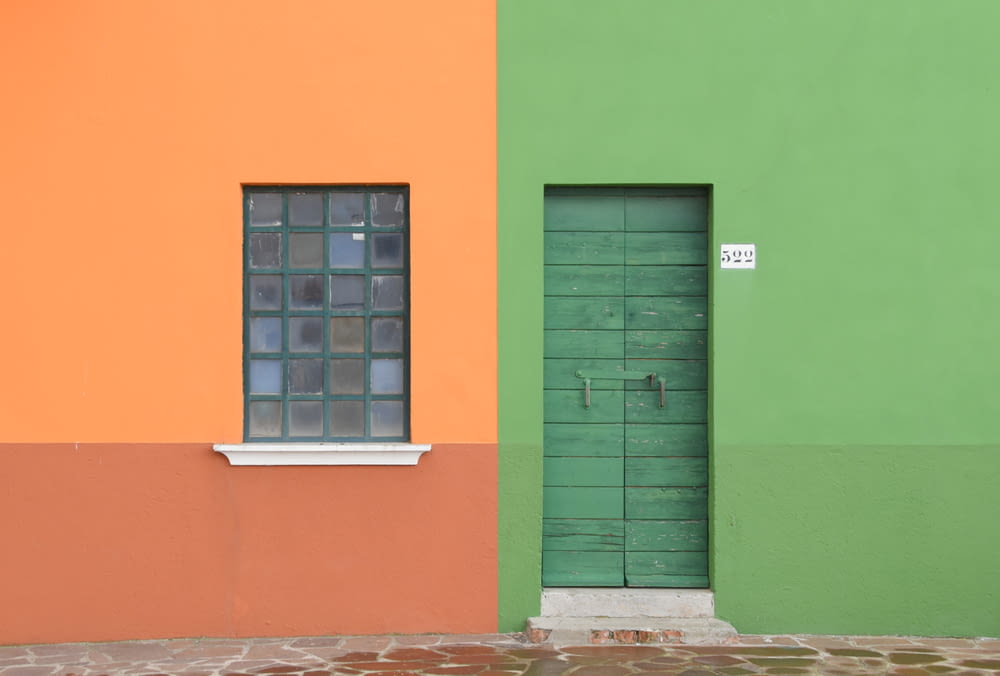 a green and orange building with a window