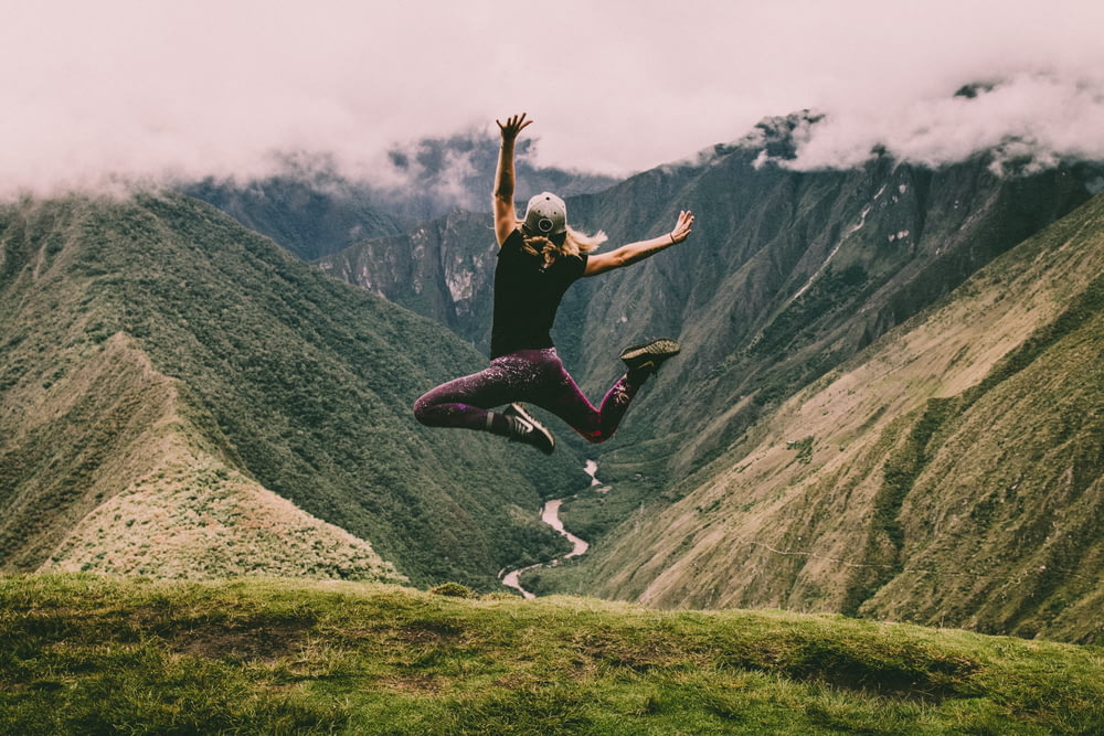Frau springt auf grünen Bergen