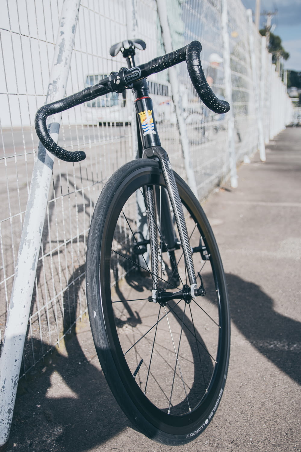 vélo de route noir et blanc garé à côté d’une clôture métallique