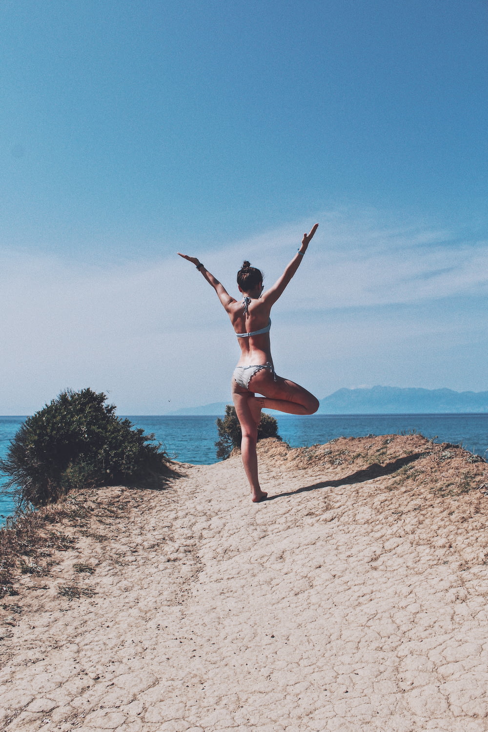 Una mujer en bikini haciendo una pose de yoga en una playa