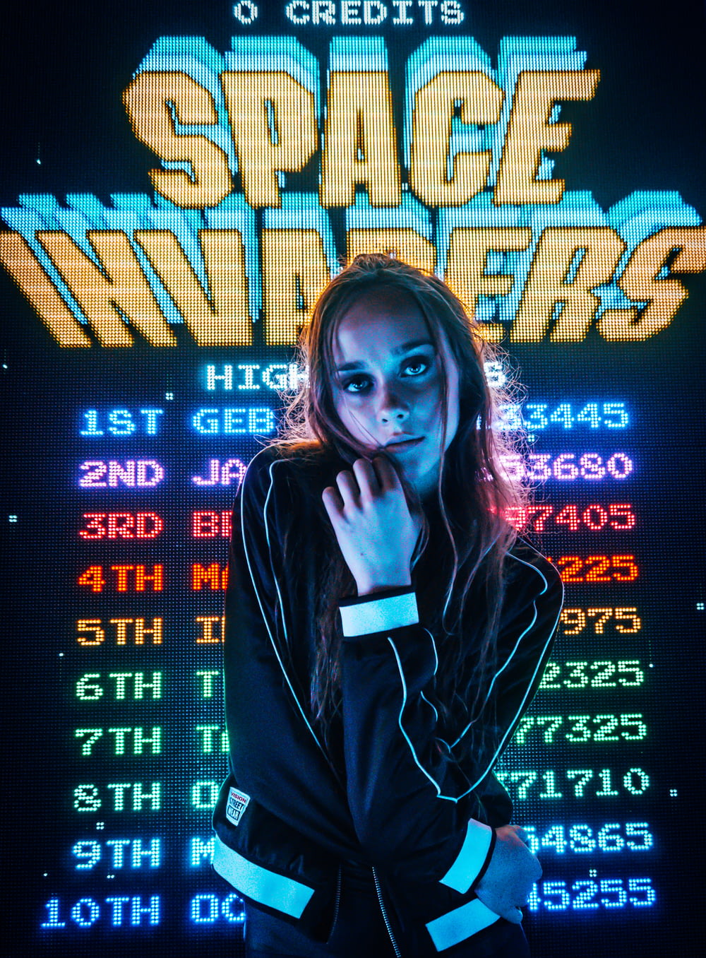 woman posing for photo in front of Space Invaders scoreboard