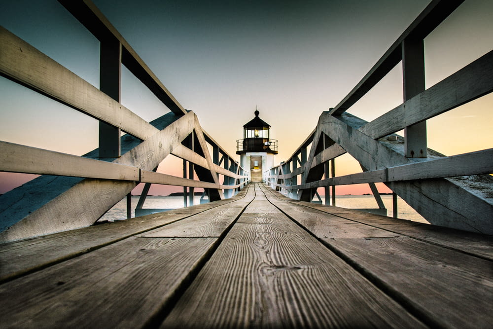 a wooden pier with a light house in the background