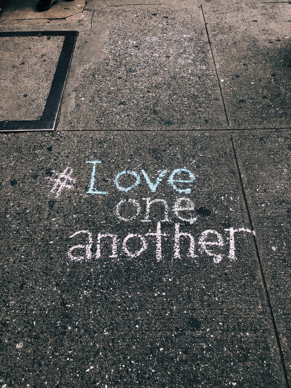Amaos los unos a los otros con tiza escrita en el suelo de cemento