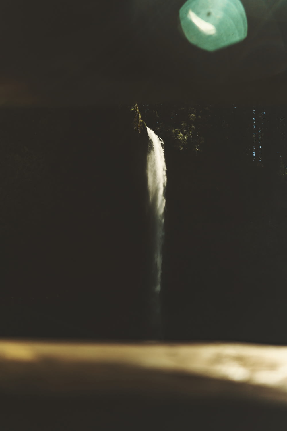 夜の滝の上を飛ぶ緑のフリスビー